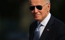 A close-up of Joe Biden. He is wearing a suit and tie with an American flag pin, and aviator sunglasses.