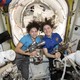The astronauts Jessica Meir and Christina Koch pose with space drills before suiting up for their spacewalk.