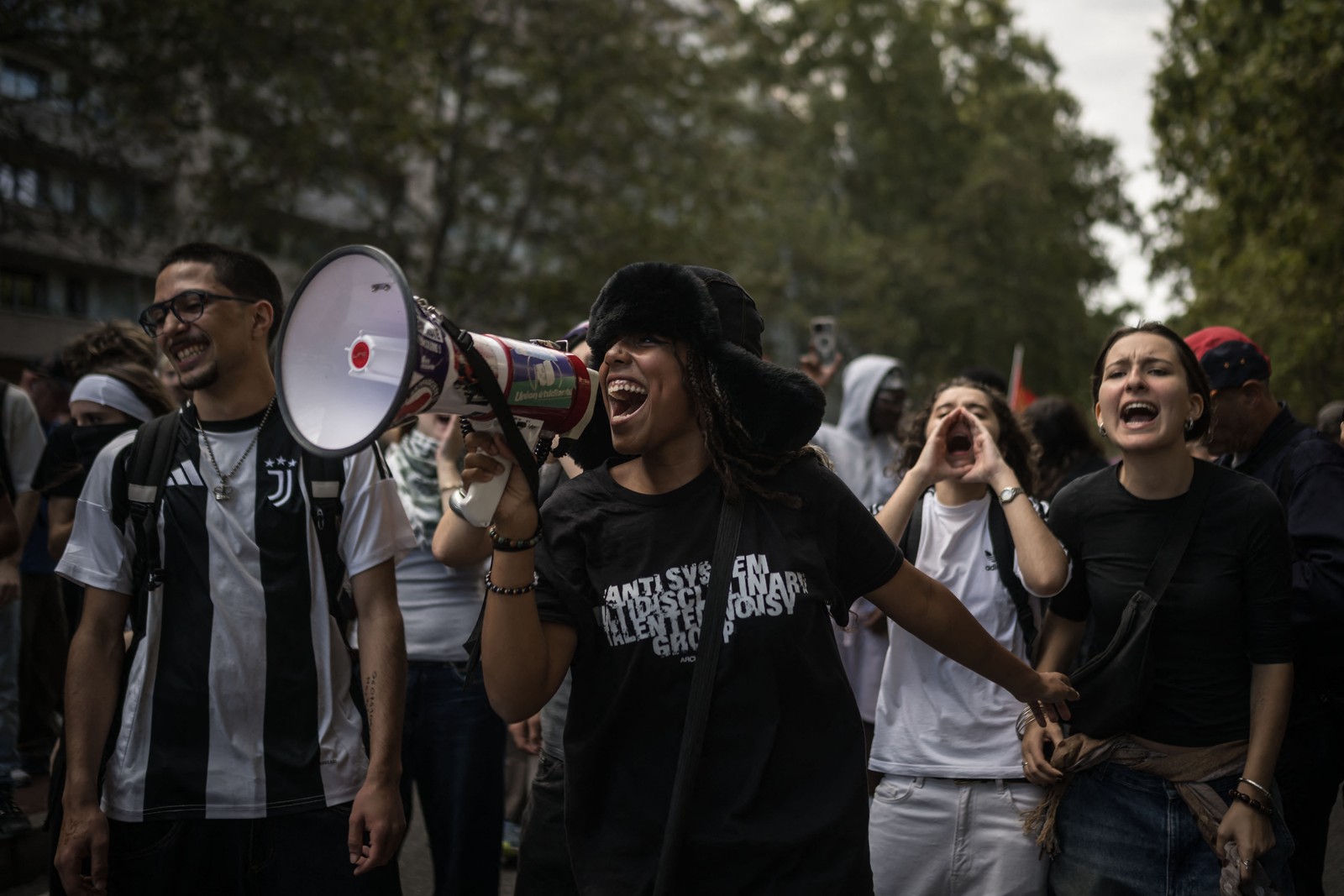 Protesters march while chanting. One, at the center, holds a megaphone.