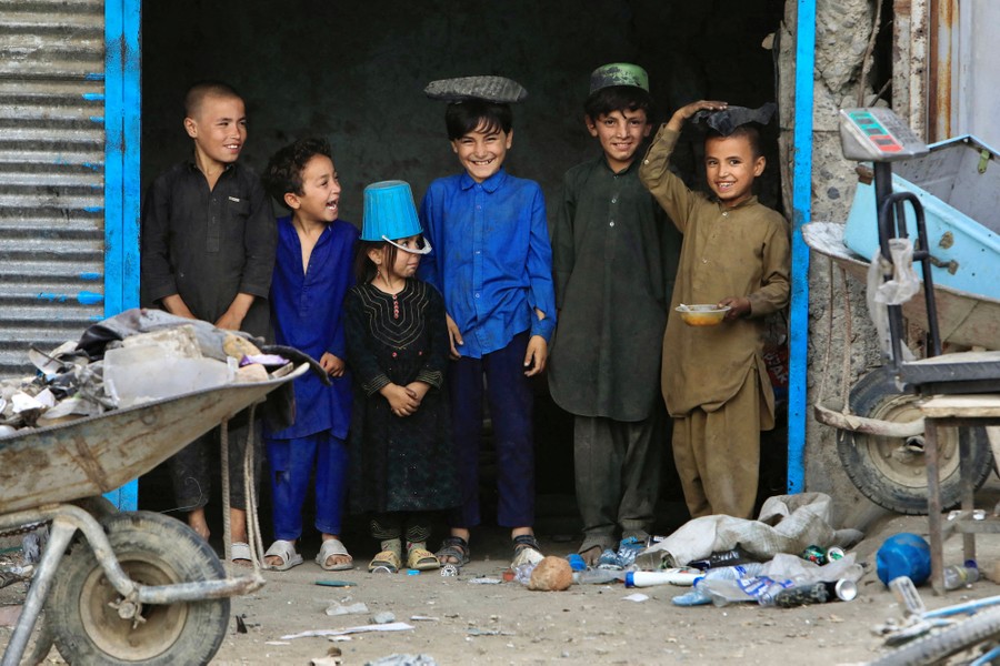 Six children stand side by side, playfully wearing various items on their heads.