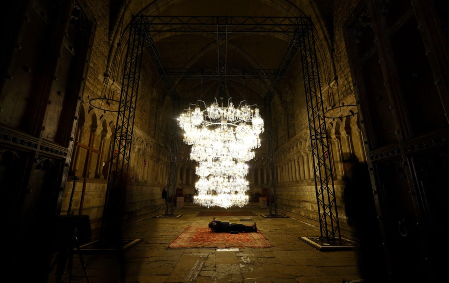 A photographer gets a shot from beneath a massive chandelier hanging low inside a cathedral.