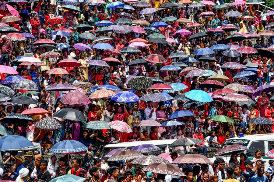 Hundreds of people gather, many carrying colorful umbrellas.