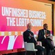 Two men at The Atlantic Festival in front of a sign that reads "Unfinished Business: The LGBTQ Summit."