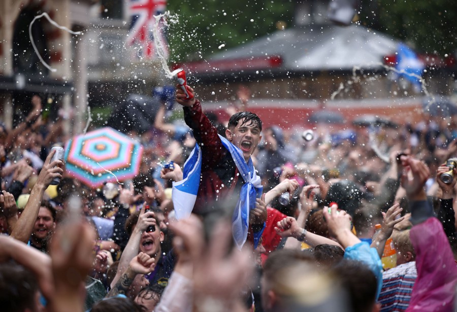 A large crowd of fans celebrate and throw beer in the air.