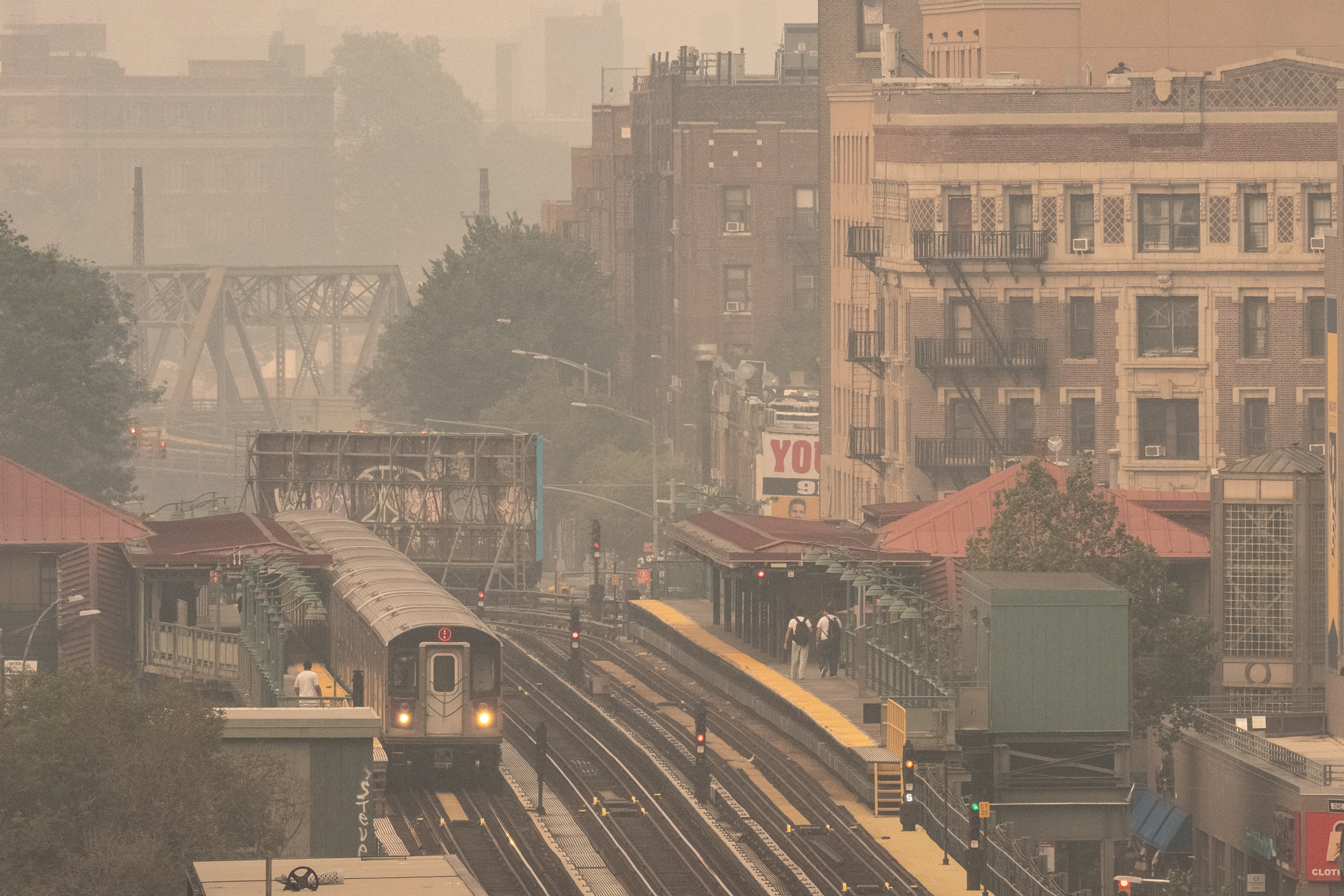 An above-ground subway station in the Bronx, seen under a smoky sky