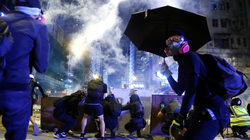 Protesters take cover behind boards during a protest in the Mong Kok area of Hong Kong.