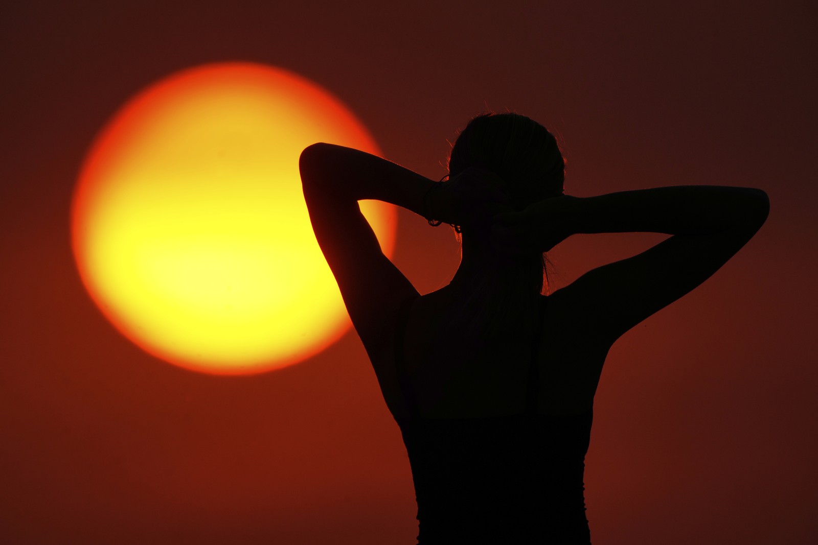 A person stands silhouette in front of the sun.