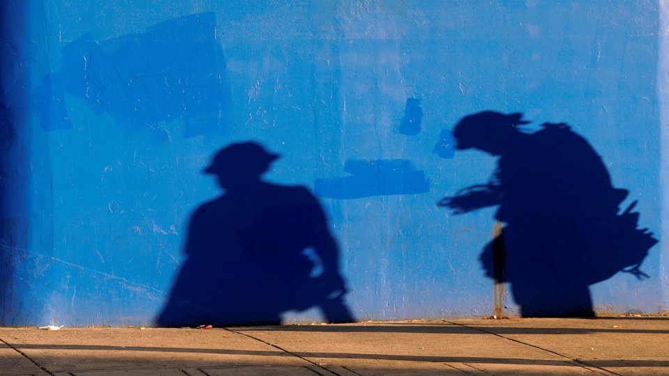 The shadows of construction workers against a plain blue wall