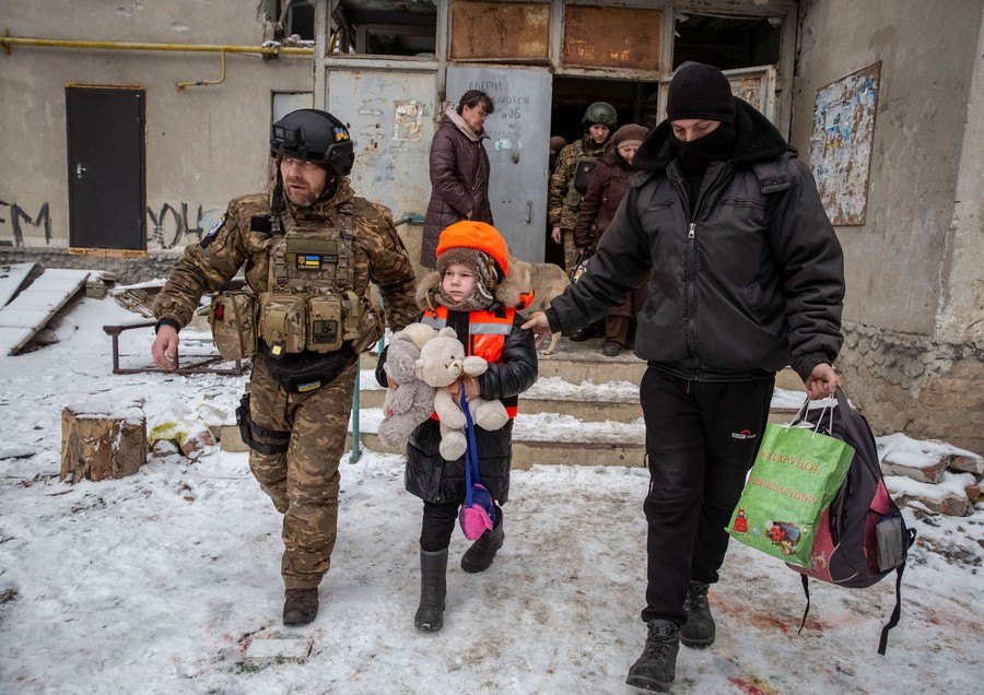 Soldiers escort a child and her family out of an apartment building.