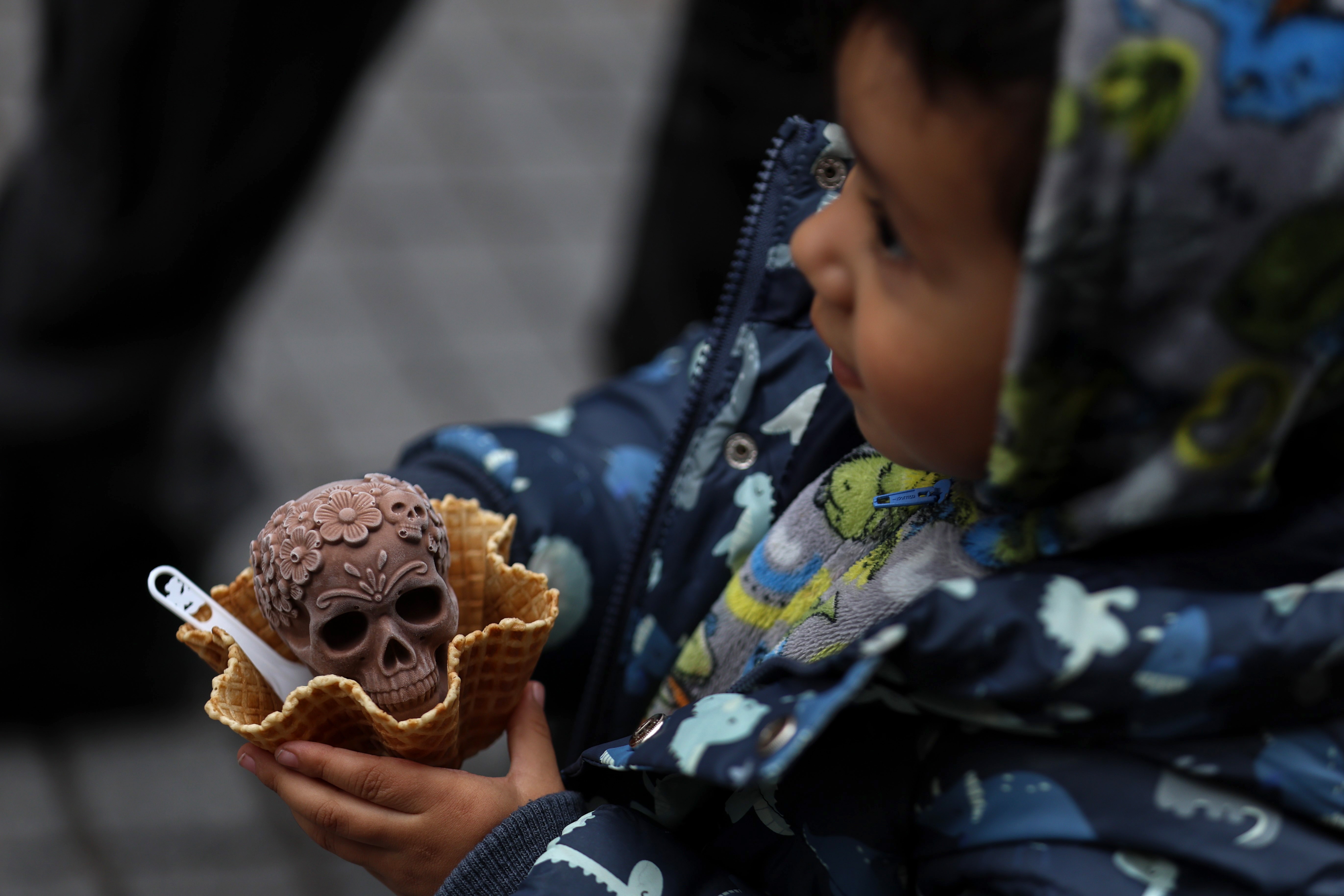 A child holds a skull-shaped ice cream treat.