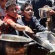 Palestinian youths shove to get a ration of hot food at a charity kitchen in Gaza City