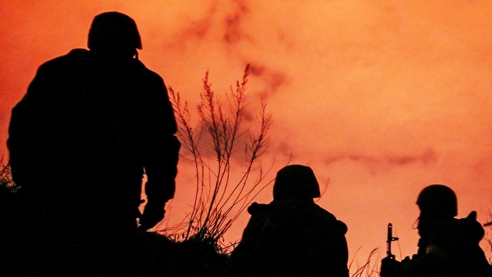 A photo showing three soldiers silhouetted against a sunset