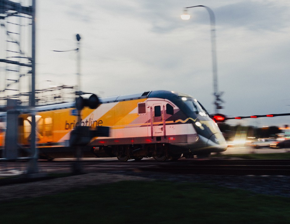 Picture of the Brightline heading Northbound through an intersection in Pompano Beach, Florida.