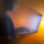 The silhouette of a man looking at a bright computer screen