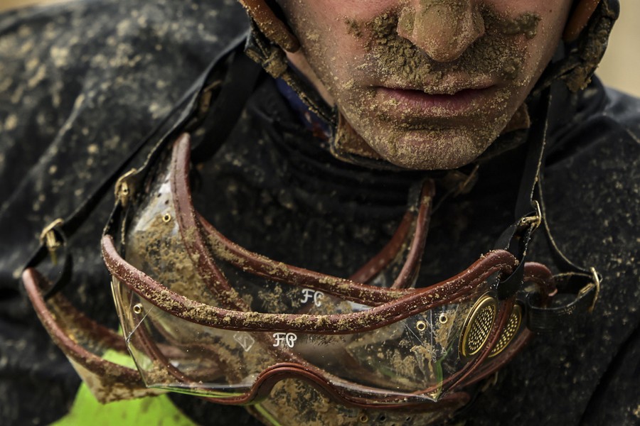 A jockey's face and goggles covered in mud