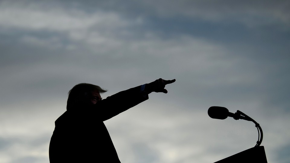 Silhouette of Donald Trump speaking at a lectern with his arm in the air