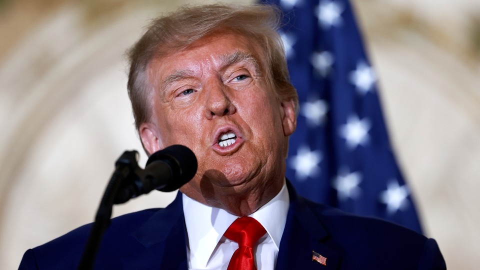 Donald Trump speaking at a microphone with a flag in the background