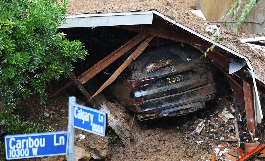 Mud covers a smashed garage and a car inside it.