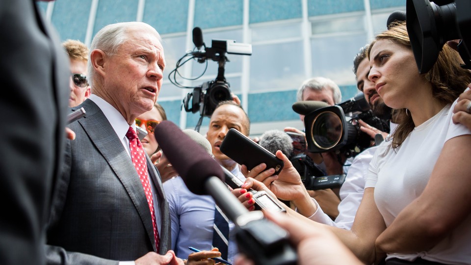 Jeff Sessions surrounded by press, some of whom are carrying microphones and video cameras.