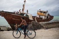 Children playing on the rusting remains of a wrecked ship that was lifted and smashed onto the town's sea wall during a king tide in February 2015.