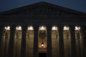 Photograph of the Supreme Court building at dusk with a hanging lantern and lights illuminating the entrance