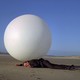 A man lays on the ground in front of a big white ball