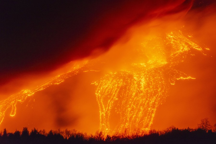 Lava flows down the side of a volcano at night.