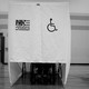 A person using a wheelchair votes at a wheelchair-accessible voting booth.