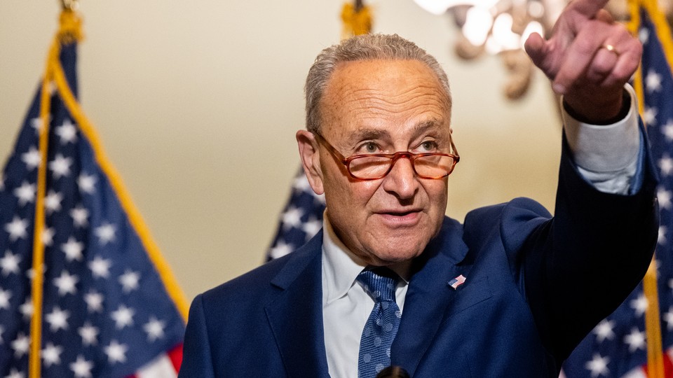 Senator Chuck Schumer pointing in front of American flags