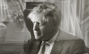 Photo: Prime Minister Boris Johnson seated, with a superimposed reflection through glass, 10 Downing Street, May 2021