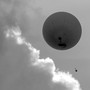A black-and-white photo of a high-altitude weather balloon, as seen from below