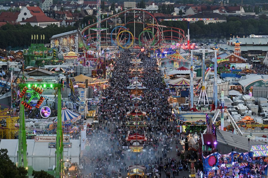 An elevated view of a crowded festival, featuring many tents and carnival rides