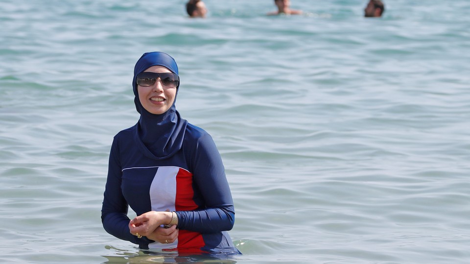 A woman in a tri-color burkini swims in the ocean in Cannes, France.