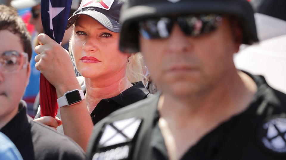 Standing behind a man in a helmet, a woman holds a flag at a rally in Charlottesville, Virginia