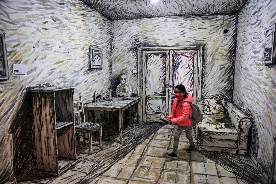 A girl walks inside a room with the walls and furnishings decorated as if they were a painting.