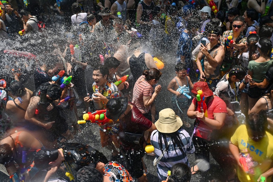 A crowd of people celebrate during a water festival, spraying and splashing one another with water.