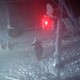A person stands on a street corner at night in the snow.