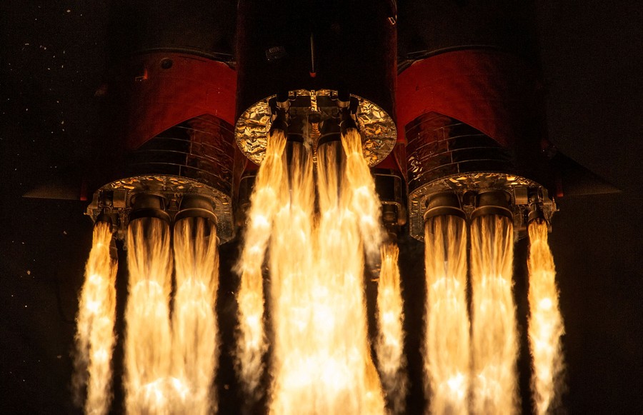 A close view of flames erupting from the engines of a rocket during a launch.