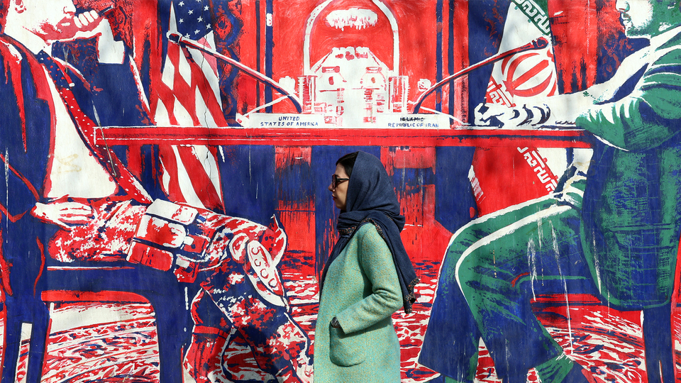 A woman walks in front of a red, white, blue, and green mural of a negotiating gable.