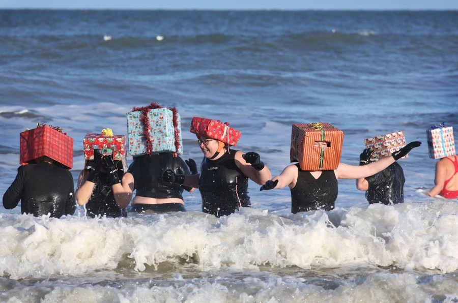 Half a dozen women wade into the surf, wearing gift-wrapped boxes on their heads.