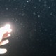 a brightly lit hand reaching out to the dark sky, the lens smudged with rain drops