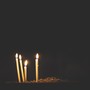 Four candles burn against a dark backdrop.