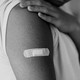 Photo of someone's upper arm with a post-injection Band-Aid