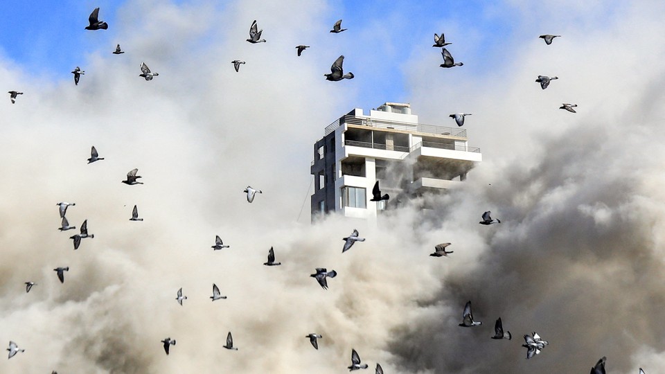 Pigeons fly away after an Israeli rocket hits a building in Beirut