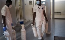Two people who work for an emergency mobile service in Dakar, Senegal, carry oxygen tanks in a hallway