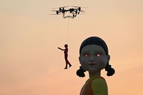 A drone flies a human figure past a very tall statue of a doll with glowing eyes.