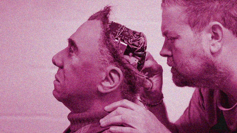 A man checks out a computer embedded in the head of another man