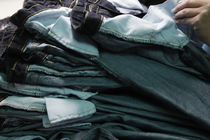 A hand sorts through a stack of jeans.