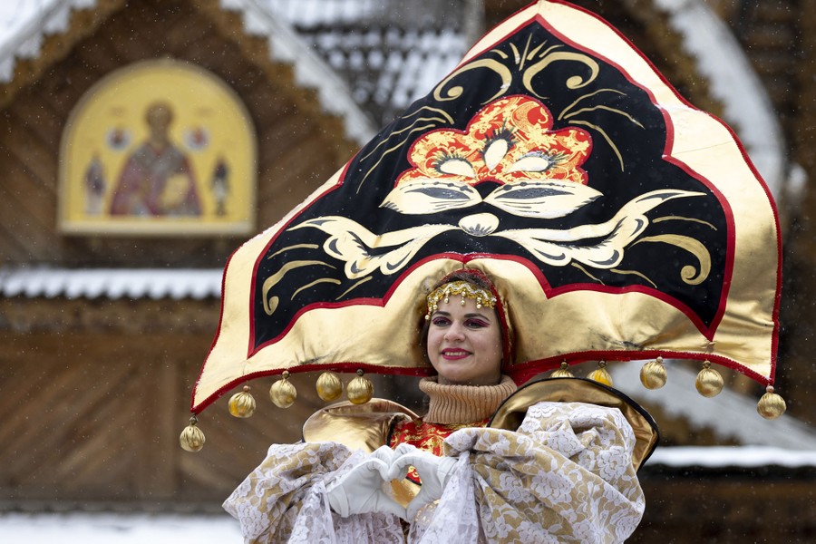 A performer wears an enormous ornate hat and costume.