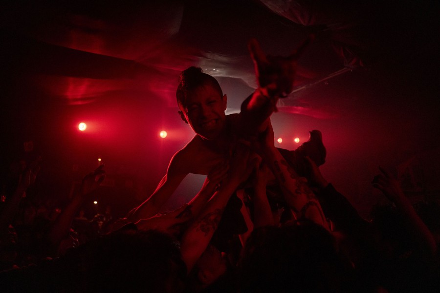 A person is lifted by a crowd inside a small venue during a concert.